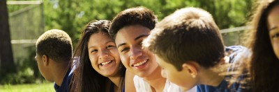 Group of racially diverse boys and girls lying on grass and conversing.