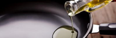 Vegetable oil is poured from a bottle into a frying pan.